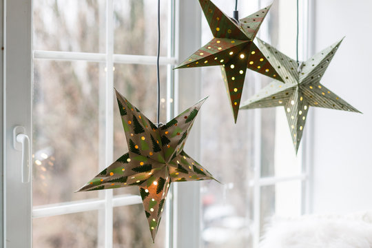 New year and Christmas concept, decorative paper stars hanging beside the window