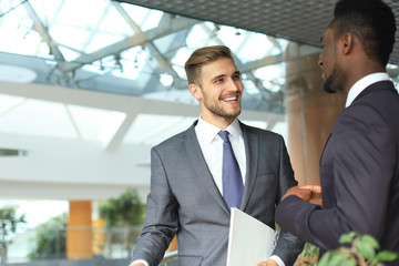 Fototapeta premium Two multinational young businessmen discussing business at meeting in office.