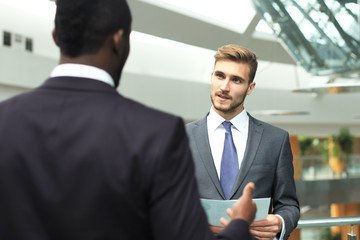 Two multinational young businessmen discussing business at meeting in office.