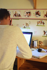 Man working with laptop on wooden table in children room in home. Working from home and freelancer concept.