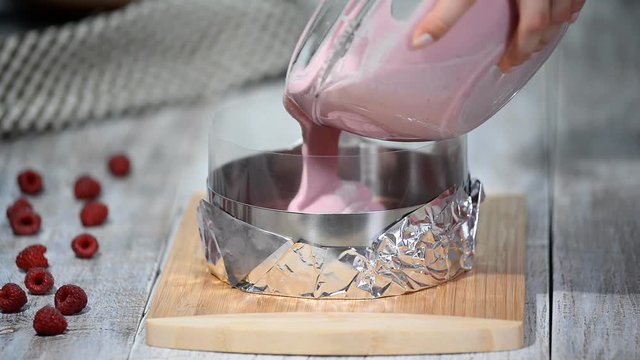 Making sweet raspberry mousse cake.