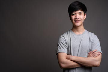 Young handsome Asian man smiling with arms crossed