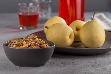 Mix of nuts of different varieties in a black bowl on the background of Japanese pears.