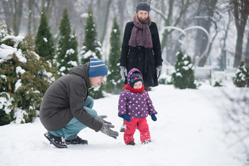 Fototapeta na wymiar Family with a small child walk in the park in winter