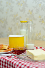 Butter, toast, jam, hot milk in a yellow mug is a healthy and nutritious homemade breakfast.