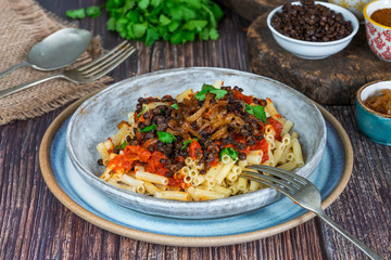 Kushari - Egyptian vegetarian dish with lentils, spiced tomato sauce and macaroni topped with fried onions