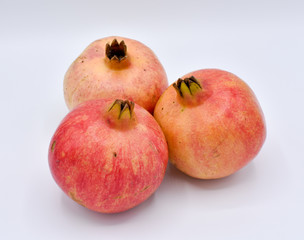 THREE DELICIOUS POMEGRANATE AT A BUNCH ON A WHITE BACKGROUND