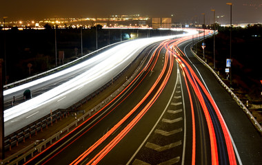 Fototapeta na wymiar DIFFERENT TRAFFIC LIGHTS OF VEHICLES IN A MOTORWAY WITH THE LIGHTS OF THE CITY AT THE END