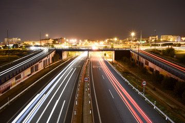 DIFFERENT TRAFFIC LIGHTS OF VEHICLES IN A MOTORWAY WITH THE LIGHTS OF THE CITY AT THE END