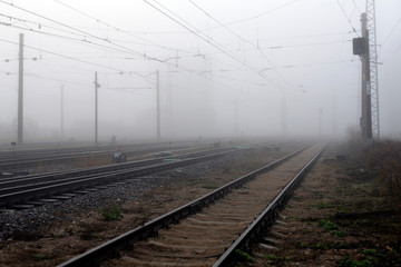 Crossing railways disappearing  fading away in the mist in autumn morning