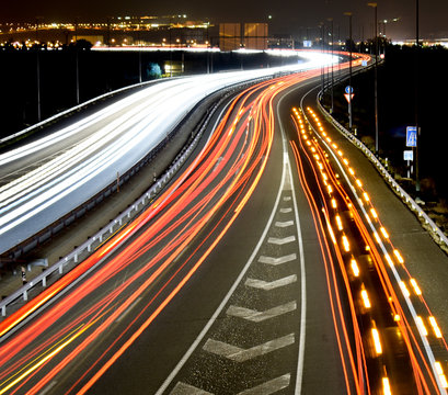 DIFFERENT TRAFFIC LIGHTS OF VEHICLES IN A MOTORWAY WITH THE LIGHTS OF THE CITY AT THE END © RUBENBON10