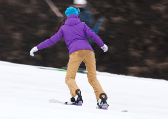 Girl snowboarding from the mountain in winter