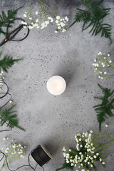 Christmas and New Year composition with single white candle on a table among winter decorations. Flat lay, top view.