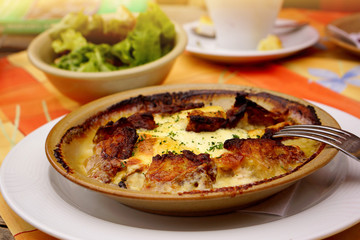 Traditional winter dish, potato gratin, baked potatoes with cream, bacon and melted cheese 