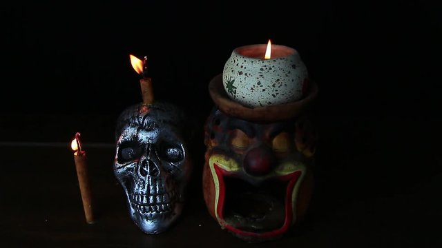 Halloween dark scary horror story ideas concept with jocker candle light and silver skull human isolated on black background