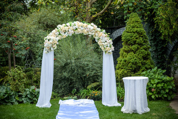 Beautiful wedding ceremony outdoors. Decorated chairs stand on the grass. Wedding arch made of...