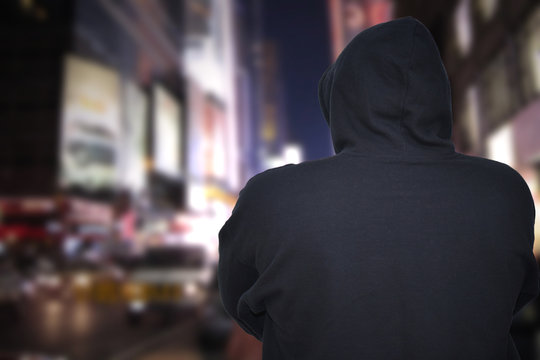 dangerous man standing on a city street with black hoodie