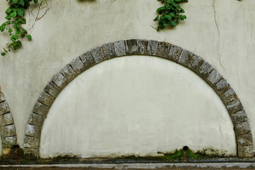 A walled door with a stone arch e against the background of an old beige plastered wall, photo...