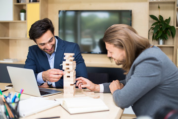 Fototapeta premium Team of young business people build a wooden construction in the office