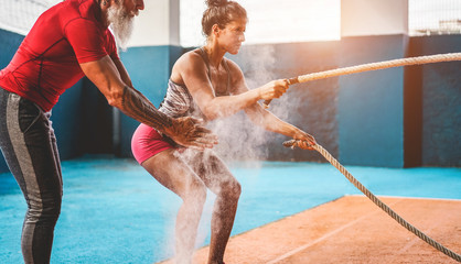Fit woman with battle rope in functional training fitness gym