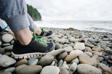Girl in sneakers sitting by the sea, traveling
