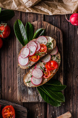 Homemade bread with fresh creame, herbs and radishes