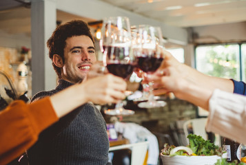 Group of young people celebrating Christmas party dinner with clinking glass of wine and selfie