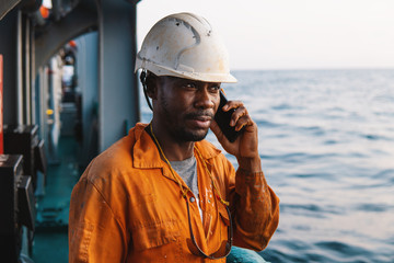 Marine Deck Officer or seaman on deck of vessel or ship . He is speaking on the mobile cell phone