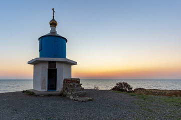 Fototapeta na wymiar Magnificent landscape overlooking the sea with the setting sun and the old chapel