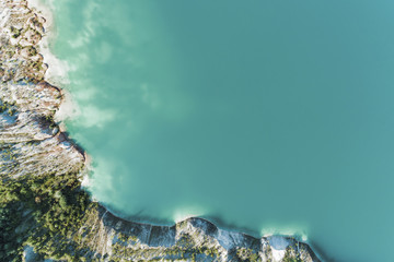An old gypsum quarry filled with blue and pure water. Aerial view, from top to bottom