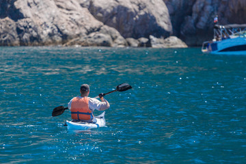 Adventure on a Kayak in the sea. Man Kayaking near the rocky island.