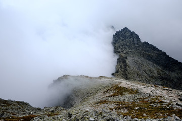 peak of Rysy mountain covered in mist. autumn ascent on hiking trails