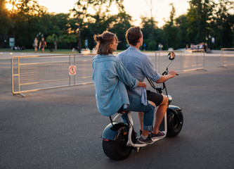 Lovely young couple driving electric bike during summer. Modern city dating and transportation