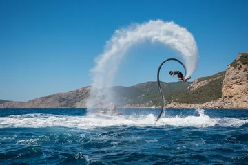 Deurstickers Flyboarding and seariding on the Sea near the mountain island. Water summer extreme sports. © kuznetsov_konsta