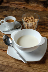 The bowl with milk, glass of dry cornflakes and coffee