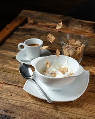 Cornflakes are falllig into the bowl with milk