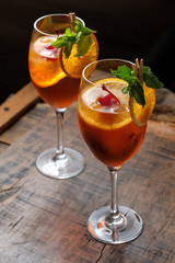 Two glasses of red cocktail with orange slice and cherry