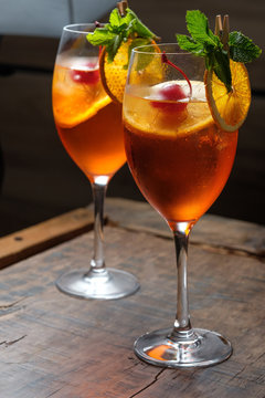Two glasses of red cocktail with orange slice and cherry