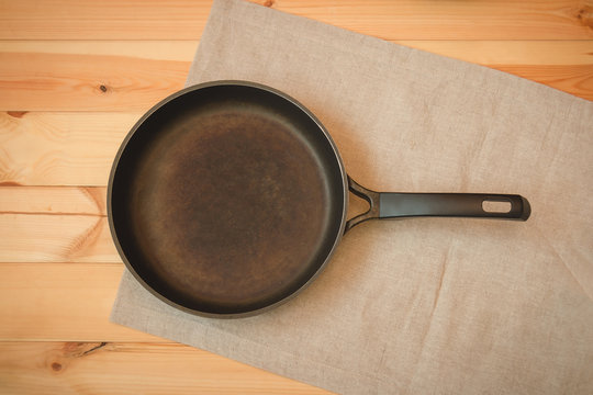 Empty iron frying pan on wooden background. Top view with copy space.