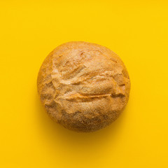 Freshly baked bread on yellow colored background, top view