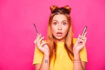 Sexy woman with long hair in yellow t-shirt on a pink background applying make up, making amazed emotions