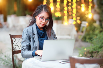 cute and charming businesswoman with glasses working on laptop computer from restaurant or cafe