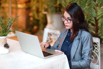 cute and charming businesswoman with glasses working on laptop computer from restaurant or cafe