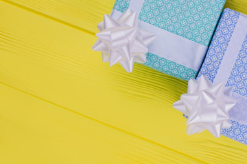 Gift boxes and copy space. Two gift boxes in blue and turquoise patterned paper with bow on yellow...