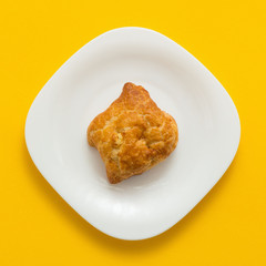 Freshly baked butter croissant on yellow colored background, top view