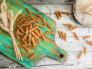 Wholemeal pasta on green rustic wooden chopping board