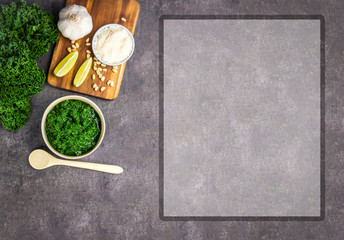 Pesto from kale on grey background with a frame for recipes. Top view