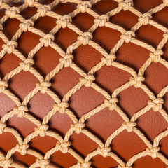 Luxury brown leather covered with beige rope net. Beautiful background. Closeup.
