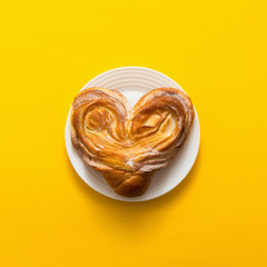 Sweet bun on yellow background, tiop view, flat lay