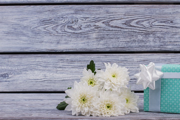 Gift box and chrysanthemum flowers on wooden background. Bunch of white flowers and gift box on rustic wood with copy space. Happy Birthday card.